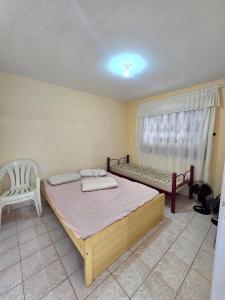 a bedroom with a bed and a chair and a window at Casa em Shangri-la próxima ao mar in Pontal do Paraná