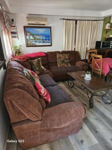 een woonkamer met een bruine bank en een tafel bij El patio de rosy in Maldonado