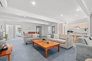 een woonkamer met banken en een tafel bij Forresters Dunes - Downstairs in Wamberal +12 foto's