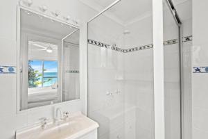 een witte badkamer met een wastafel en een spiegel bij Forresters Dunes - Downstairs in Wamberal