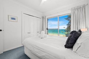 een slaapkamer met een groot wit bed en een groot raam bij Forresters Dunes - Downstairs in Wamberal