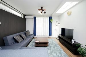 ein Wohnzimmer mit Sofa und Fernseher in der Unterkunft Higashi Rokugou WHITE / Vacation STAY 4276 in Tokio
