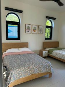 a bedroom with two beds and two windows at The Vista My Hoa in Ninh Hải