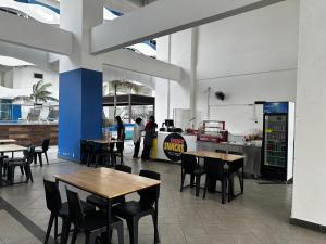 un restaurant avec des tables et des chaises et des gens en arrière-plan dans l'établissement The Wave Residences Melaka 4pax 2R1B, à Malacca