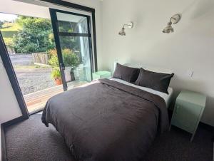 a bedroom with a large bed and a large window at Minden Retreat in Te Puna