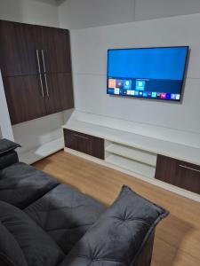 a living room with a couch and a flat screen tv at Um lar em Brasília, super aconchegante e com ar condicionado in Brasília