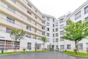 Un edificio de apartamentos con árboles en frente. en Quality Suites Valenciennes, en Valenciennes