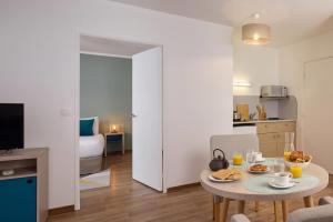 Una sala de estar con una mesa pequeña y una cocina. en Quality Suites Valenciennes, en Valenciennes