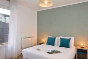 Un dormitorio con una gran cama blanca con almohadas azules. en Quality Suites Valenciennes, en Valenciennes 11 fotos más