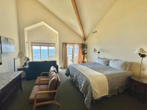 Un dormitorio con una cama y una silla y una ventana. en Turtle Rocks Oceanfront Inn, en Trinidad