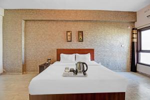 a hotel room with a bed with a tea kettle on it at Townhouse Classio Suites in Shirdi