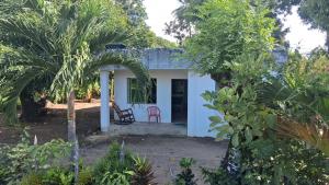 Una pequeña casa blanca con una silla roja en un jardín. en DLuchy Casa Finca Rural cerca al mar, en San Bernardo del Viento