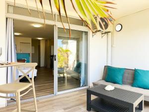 a living room with a couch and a table at Air-conditioned sea access studio, fiber optic, parking in Punaauia