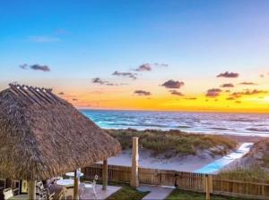 a beach with a straw hut and the ocean at Beachfront Aparthotel in Deerfield Beach with Panoramic Views of the Ocean! in Deerfield Beach