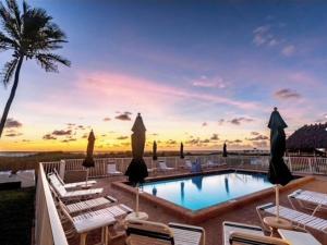 a swimming pool with lounge chairs and a palm tree at Beachfront Aparthotel in Deerfield Beach with Panoramic Views of the Ocean! in Deerfield Beach