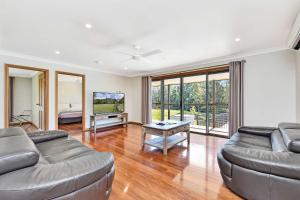 a living room with a couch and a tv at Chardonnay Escape in Pokolbin