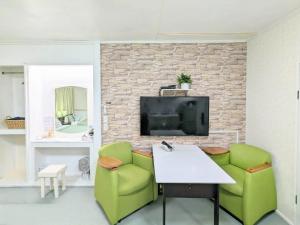 ein Wohnzimmer mit zwei grünen Sesseln und einem Fernseher in der Unterkunft Lavilla aveneu / Vacation STAY 73439 in Okinawa