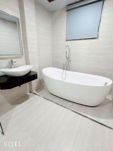 a white bathroom with a tub and a sink at One Villa Hotel 6 in Long Biên