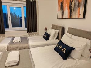 a room with three beds and a window at Garland Modern 4 Bedroom House with Garden & Parking in Kent