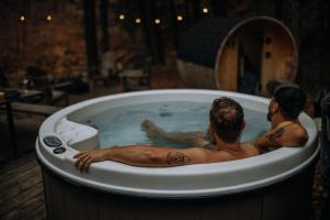 zwei Männer sitzen in einer Badewanne in der Unterkunft Le 88 Howard - Spa Sauna River & Cute Bridge in Mansonville
