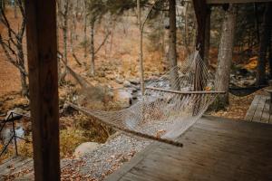 a hammock hanging from a porch in the woods at Le 88 Howard - Spa Sauna River & Cute Bridge in Mansonville