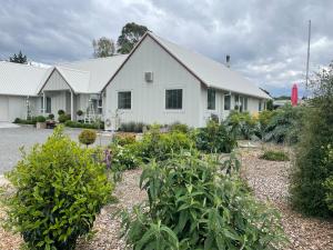 una casa blanca con un jardín delante en Oakhampton Lodge, en Kaiapoi