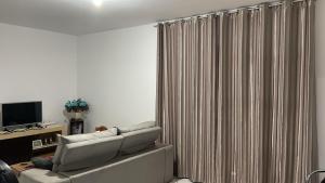 a living room with a couch and a curtain at Quarto Moderno e aconchegante em Apartamento!!! in Foz do Iguaçu