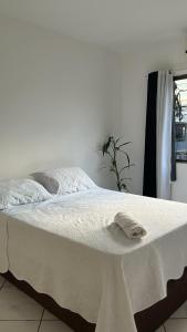 Una cama blanca con una toalla encima. en Quarto Moderno e aconchegante para hospedagem, en Foz do Iguaçu