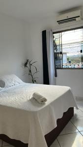 Una cama blanca con una toalla en un dormitorio en Quarto Moderno e aconchegante para hospedagem, en Foz do Iguaçu