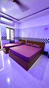 a bedroom with two purple beds in a room at Singaravelu rooms in kāraikāl