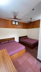 two beds in a room with wooden walls at Singaravelu rooms in kāraikāl
