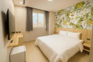 a bedroom with a bed and a painting of flowers at 星雨行館-逢甲洲際館 in Taichung