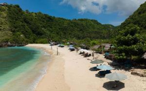 a sandy beach with umbrellas and the ocean at Villa SOWILO Penida in Polilit