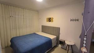 a small bedroom with a bed with a blue blanket at Apartamento 100 metros mar in Tramandaí