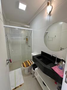 a bathroom with a shower and a sink and a mirror at Apartamento 100 metros mar in Tramandaí