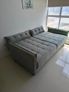 a large gray bed in a room with a window at Apartamento 100 metros mar in Tramandaí