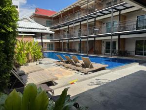 a hotel with a swimming pool with lounge chairs next to it at Celosia Chiang Mai Hotel in Chiang Mai