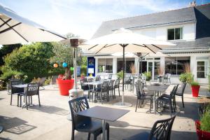 un patio extérieur avec des tables, des chaises et des parasols dans l'établissement Hôtel Restaurant Logis Coté Lac, à Savenay