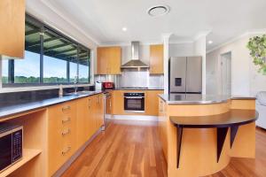 a large kitchen with wooden cabinets and a large window at Stay at Shiraz in Belford