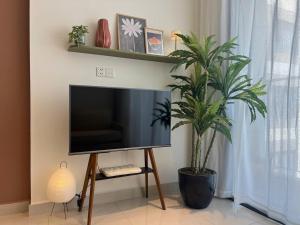 een flatscreen-tv op een stand naast een plant bij The Urban Origami S703 in Long Bình
