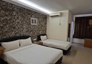 a hotel room with two beds and a wall at Hotel Grand Court Inn in Sungai Besar +9 photos