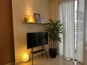 een televisie op een stand in een kamer met een plant bij The Urban Origami S703 in Long Bình +6 foto's