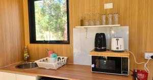 a kitchen with a sink and a microwave on a counter at Wilderness Whisper By Tiny Away in Agnes Water