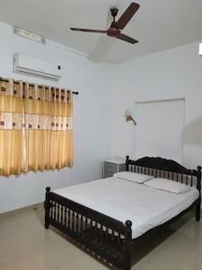 a bedroom with a bed with a ceiling fan at Akalapuzha Homestay in Kozhikode