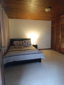 une chambre avec un lit avec une lumière sur le mur dans l'établissement Habitación con baño, parqueo y seguridad, à San José