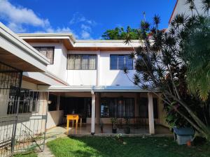 une maison blanche avec un palmier devant dans l'établissement Habitación con baño, parqueo y seguridad, à San José
