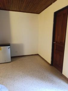 une chambre vide avec une porte et un réfrigérateur dans l'établissement Habitación con baño, parqueo y seguridad, à San José