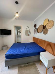 a bedroom with a blue bed and a tv at Toninhas - Condomínio Wembley Tênis F201 in Ubatuba