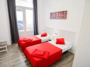 two red beds in a white room with a window at Malaga BnB in Málaga