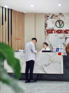 a man standing at a desk in an office at Viet Hoa Hotel & Residence Cat Ba - Rooftop Pool in Cat Ba +100 photos